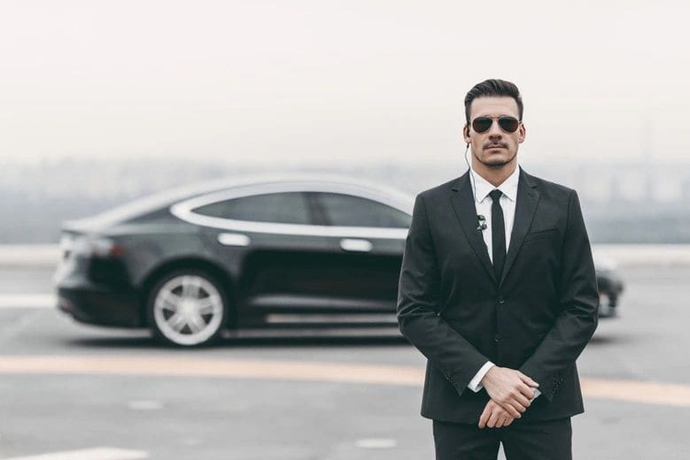 Executive protection agent beside a vehicle